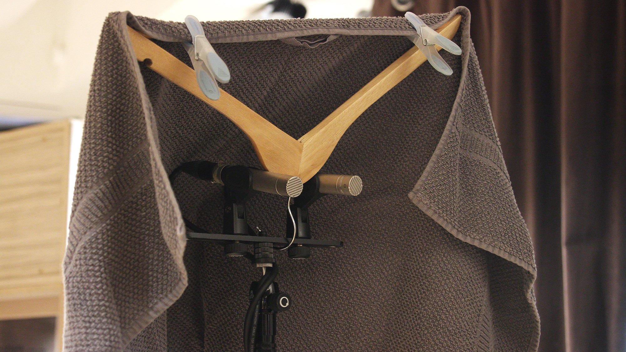 Stereo room recording technique with a pair of microphones and a towel on a coat hanger for isolation.